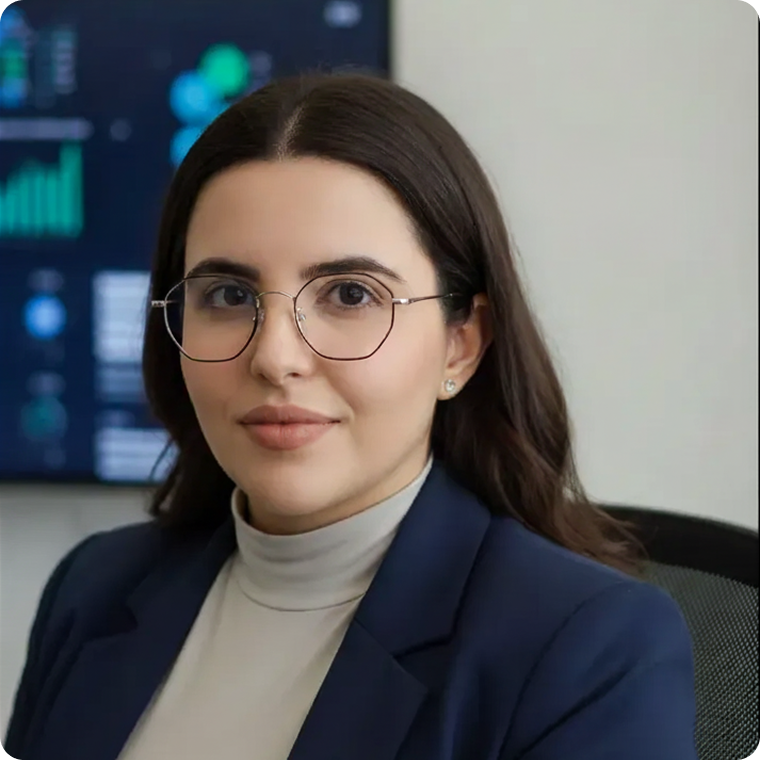 White Mediterranean-style house with a terracotta roof, surrounded by lush greenery and partially obscured by vibrant red-orange flowers in the foreground